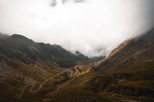 Free Breathtaking aerial view of a winding road through the majestic Carpathian Mountains in Romania. Stock Photo