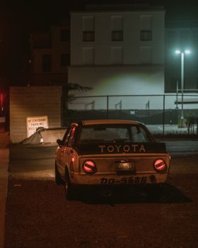 Classic Toyota car in an urban setting at night, showcasing nostalgic automotive design.