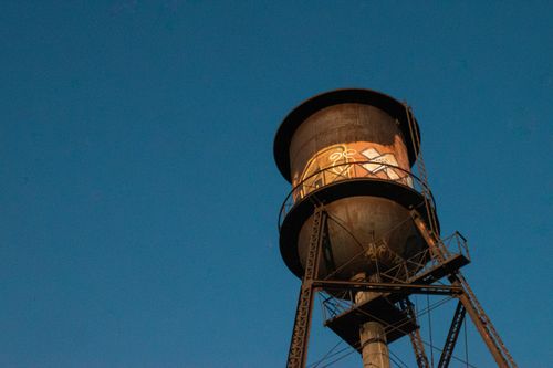Free Low angle view of a graffiti-covered water tower against a clear blue sky in Montreal, QC. Stock Photo