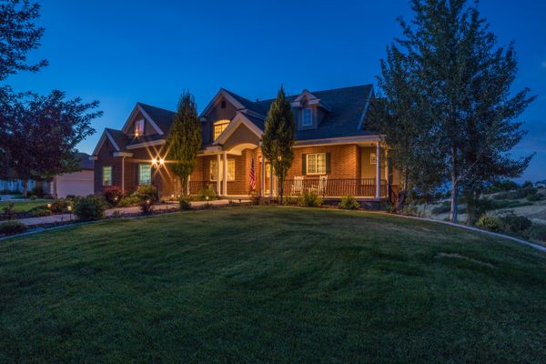A country house with lit windows surrounded by greenery at twilight — photo by Get Lost Mike on Pexels