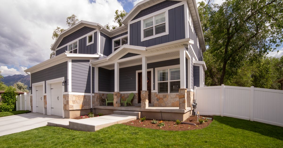 A modern two-story house with front porch and attached garage in a suburban setting.