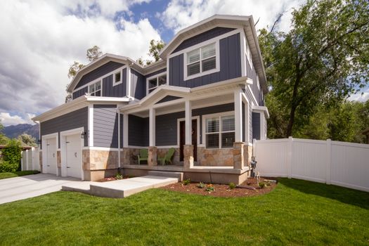 A modern two-story house with front porch and attached garage in a suburban setting.