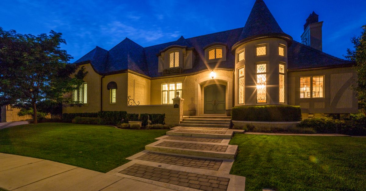 Beautiful night view of a residential home with illuminated windows and manicured lawn.