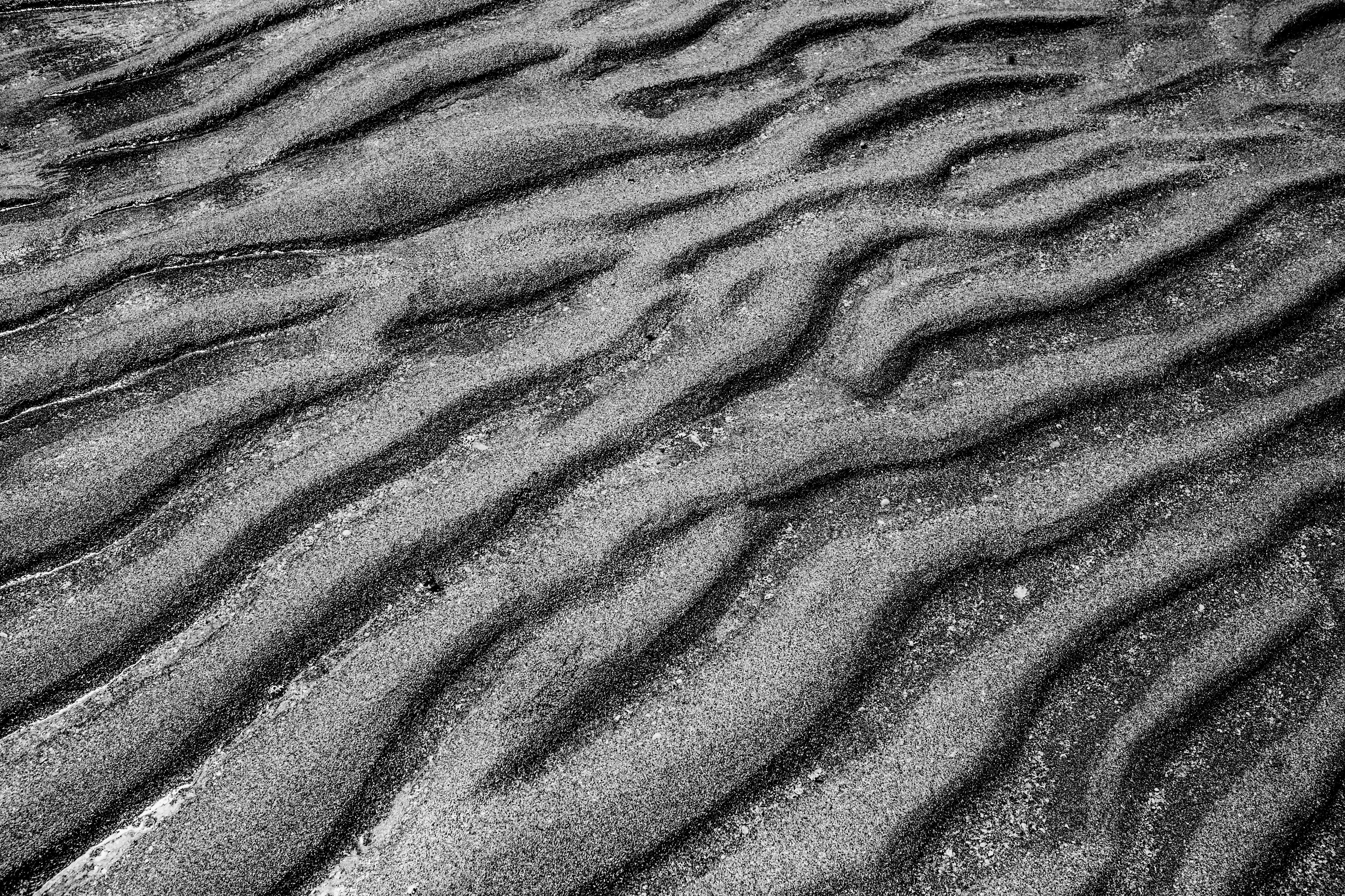 Monochromatic sand texture showcasing natural wave patterns in close-up detail.
