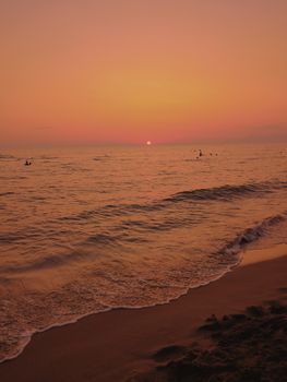 Idyllic beach sunset with tranquil sea waves and a warm, serene horizon.