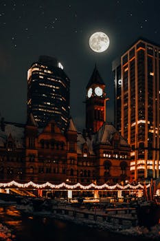 Night view of Toronto's Old City Hall with a full moon and illuminated skyline.