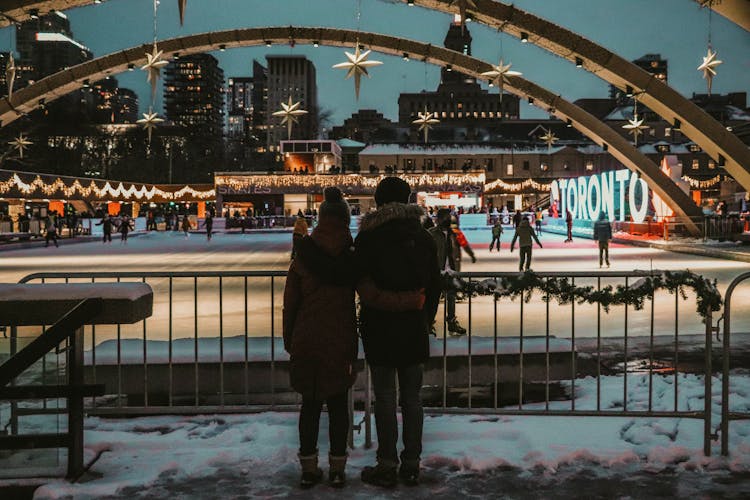 A Couple Watching Skaters In An Ice Rink