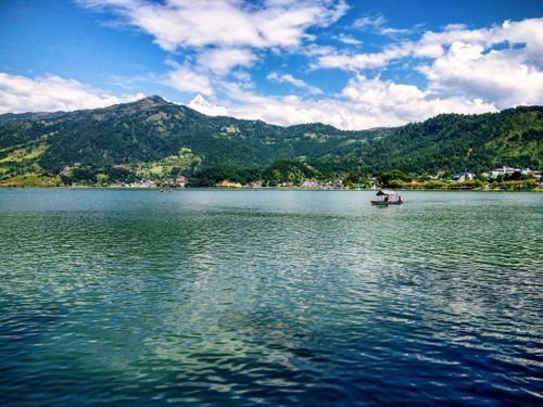 Free Serene Phewa Lake with lush mountains and clear skies in Pokhara, Nepal. Stock Photo