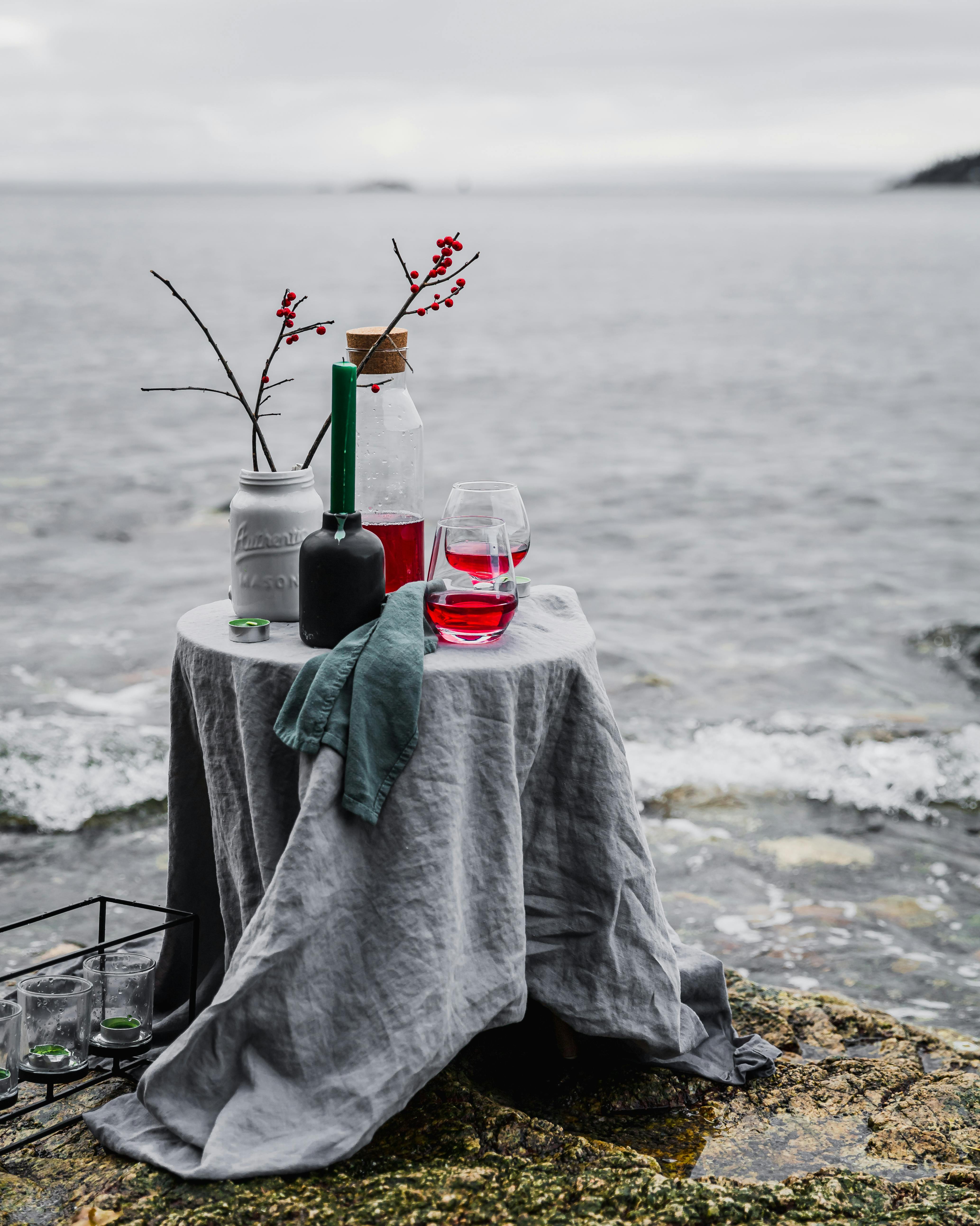 时尚的沿海餐桌布置，配有鸡尾酒和红色浆果，俯瞰大海