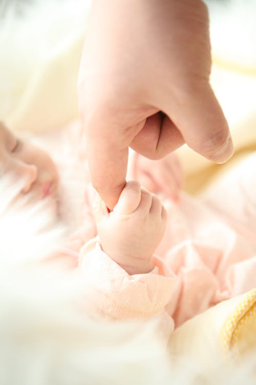 Free Heartwarming close-up of a baby holding a parent's finger, symbolizing love and connection. Stock Photo