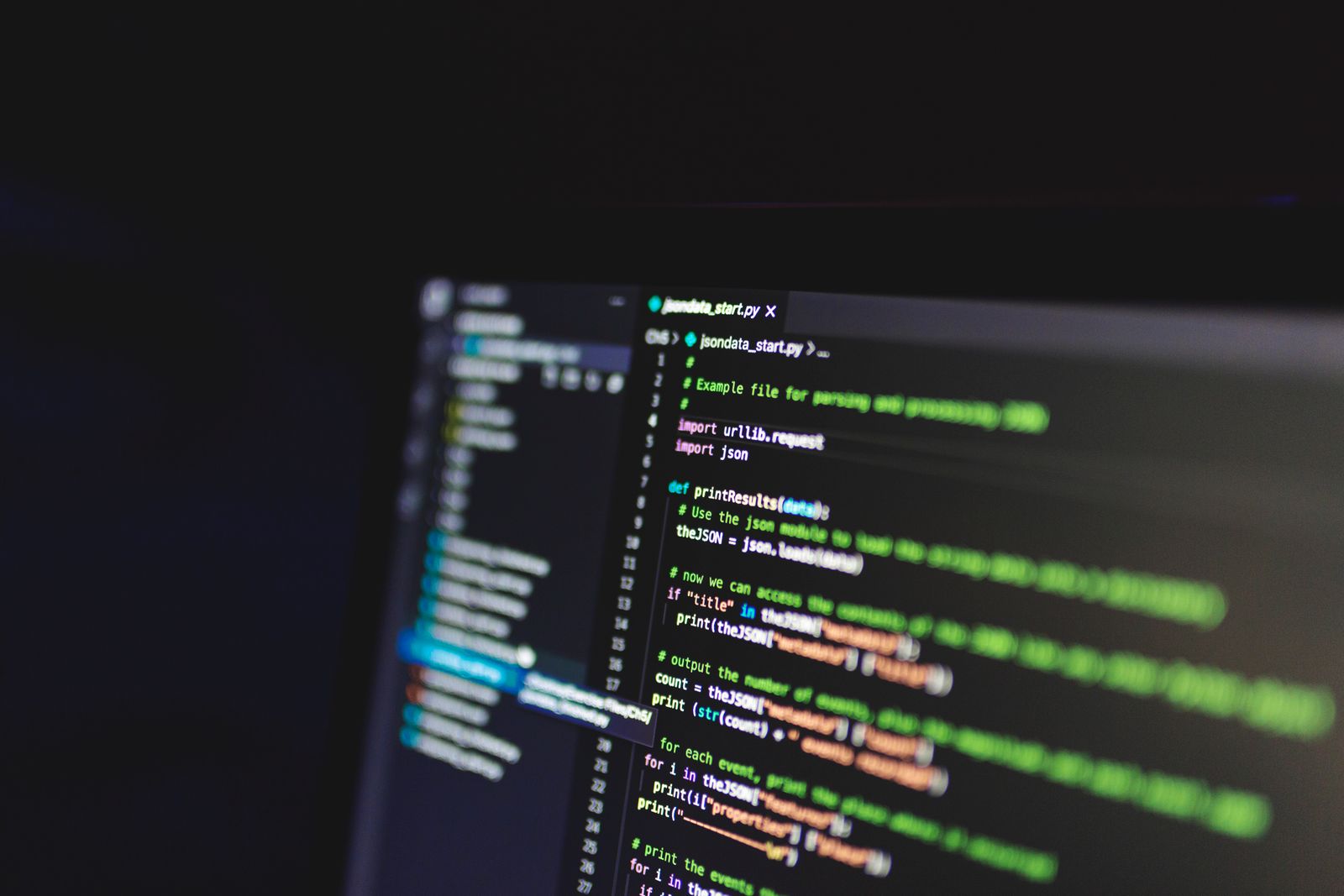 Close-up of programming code displayed on a computer screen in a dark room