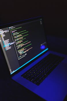 A laptop showcasing colorful code in a dark environment, ideal for tech or programming content.