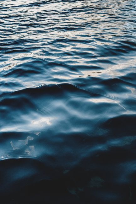 From above of rippled blue water of sea with reflection of light in daytime