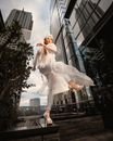 Fashionable ethnic woman doing kick standing among high towers