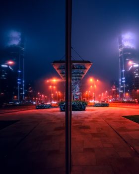 A mystical urban scene in Warsaw, Poland, with glowing red lights and foggy night atmosphere.