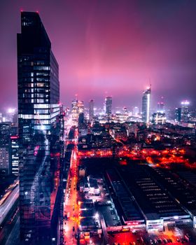 Stunning aerial view of Warsaw's illuminated skyline at night, showcasing skyscrapers and vibrant street lights.