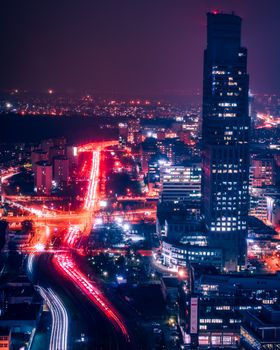 Illuminated cityscape of Warsaw at night with striking skyscrapers and bustling roads.