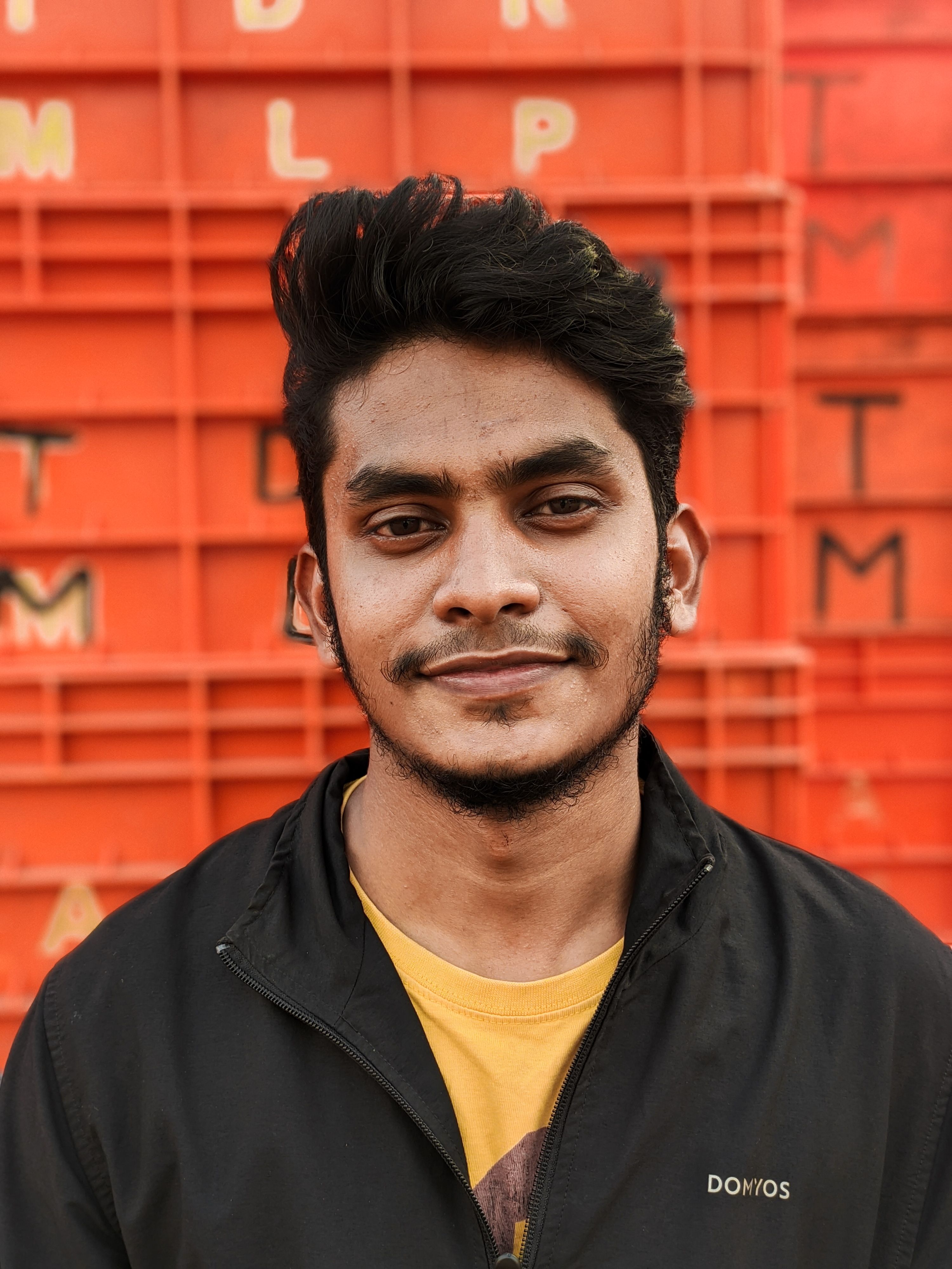 Close-up portrait of a smiling man in a jacket with a red geometric backdrop for a modern look.