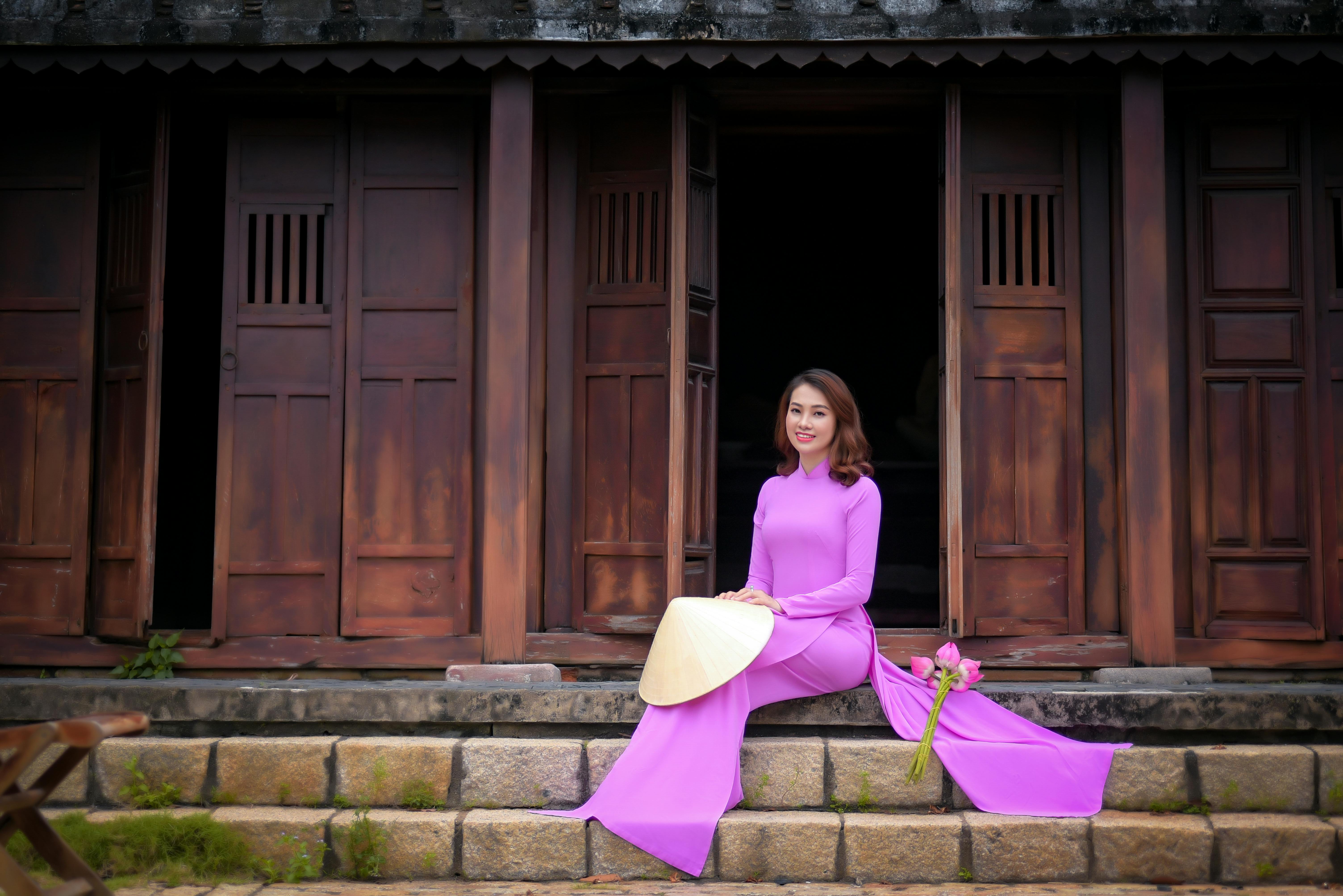 an elegant woman in an ao dai sitting on the steps
