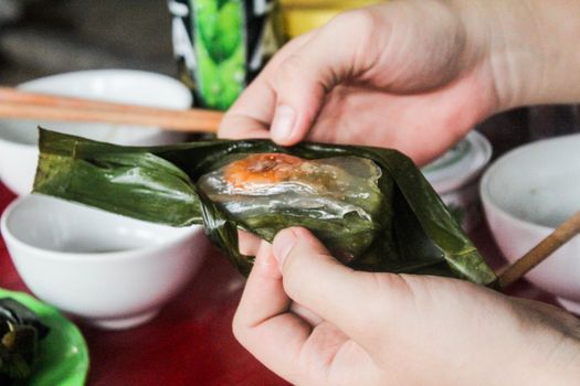 Hands unwrapping traditional Vietnamese banh bot loc, showcasing its shrimpy deliciousness.