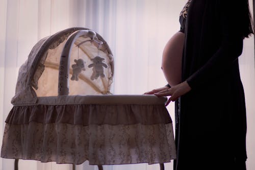 Free Pregnant Woman Standing Near White Brown Bassinet Stock Photo