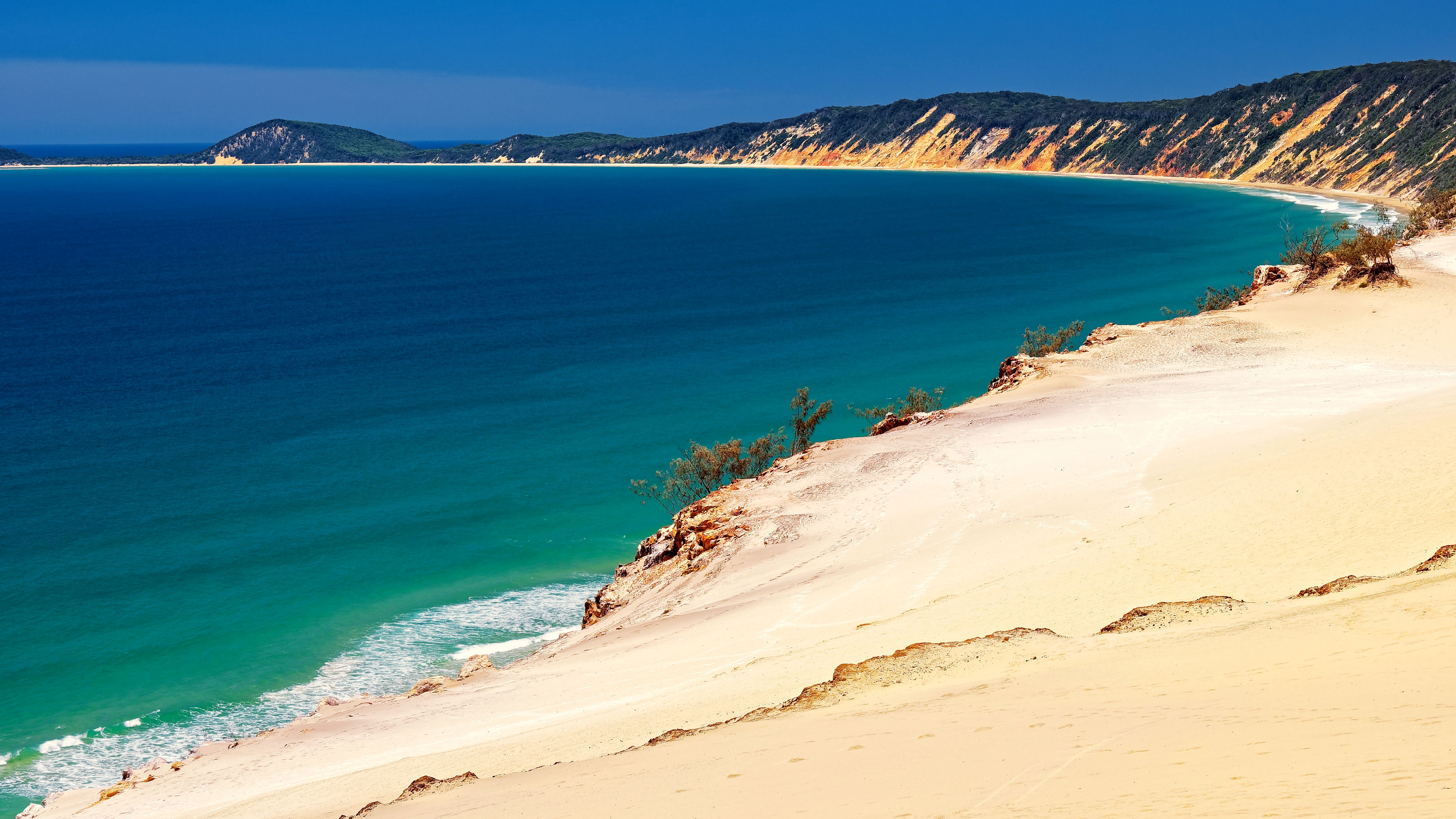 Stunning aerial view of Rainbow Beach in Australia with vibrant ocean and sand cliffs.