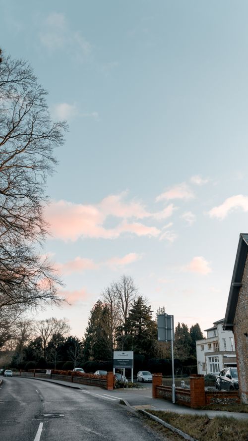 Free Charming street scene in Leatherhead, England featuring a serene blue sky and residential architecture. Stock Photo