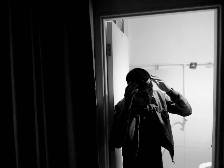 Man Touching Head In Bathroom Doorway