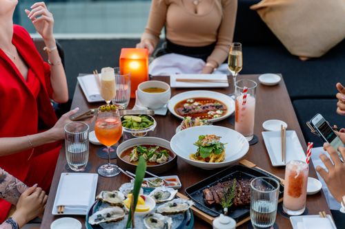 Free Chic outdoor dining in Dubai featuring diverse dishes, cocktails, and a warm atmosphere. Stock Photo