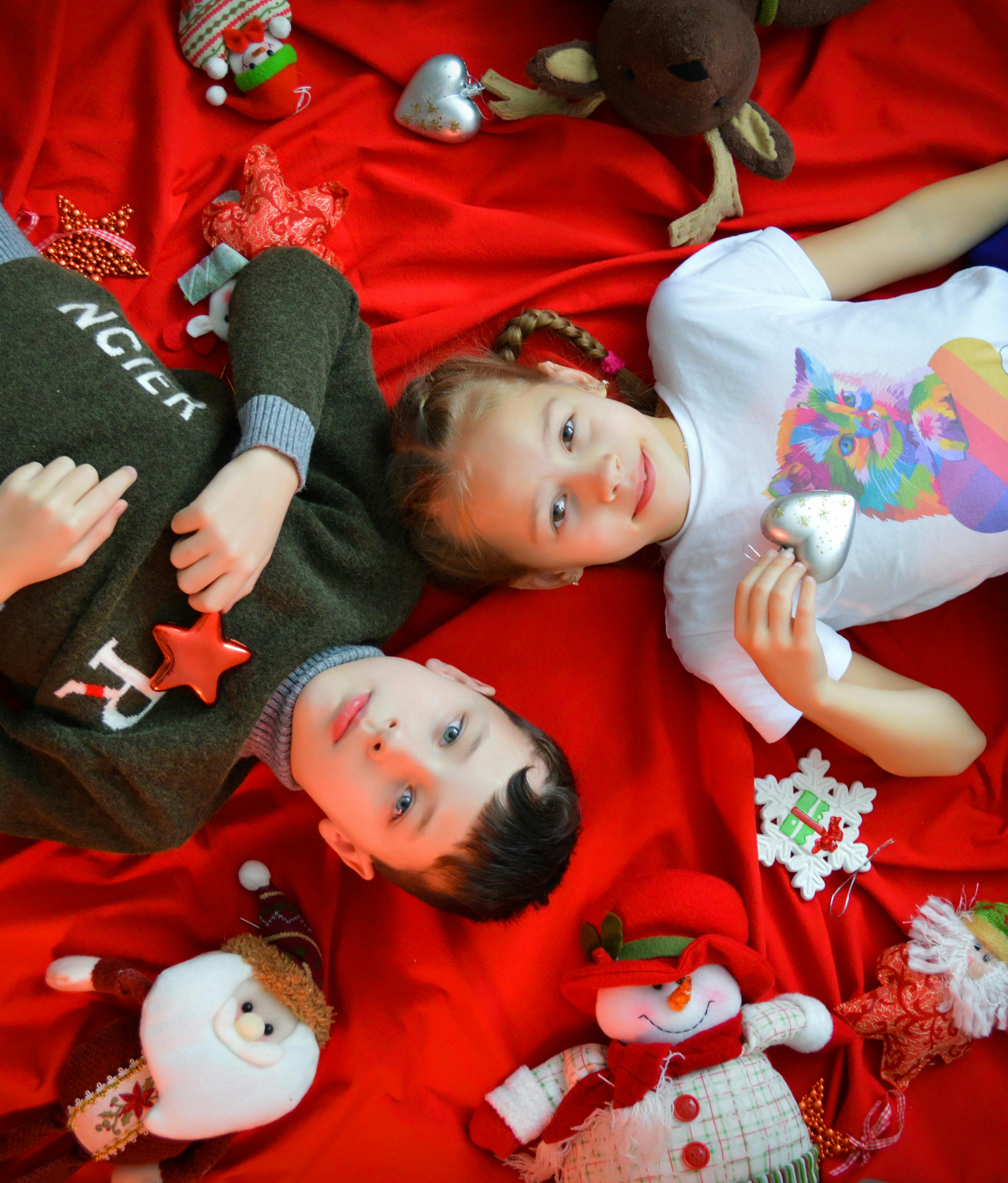 boy and girl lying on red blanket