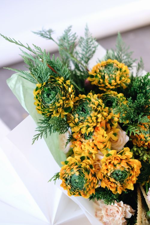 Free Bright yellow and green floral bouquet wrapped in white paper, showcasing intricate floral details. Stock Photo