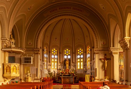 Free A beautifully lit church interior showcasing ornate architecture and vibrant stained glass windows. Stock Photo