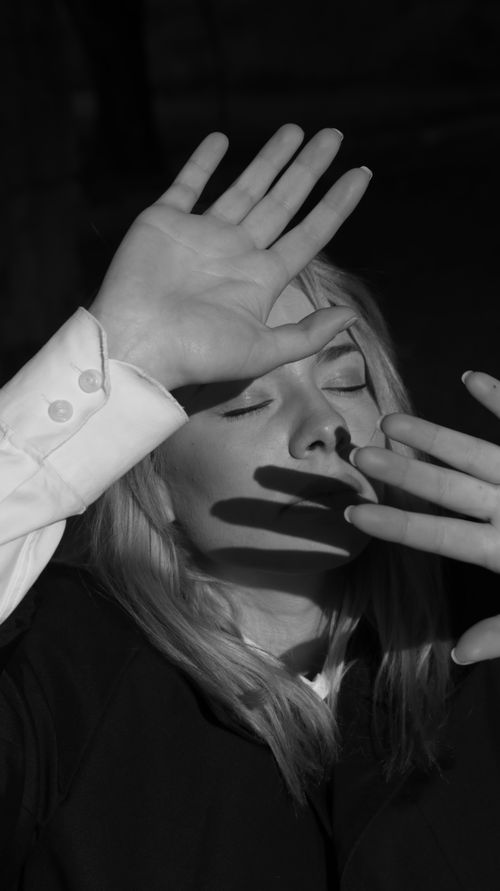 Free Artistic monochrome portrait of a woman with hands casting shadows on her face. Stock Photo
