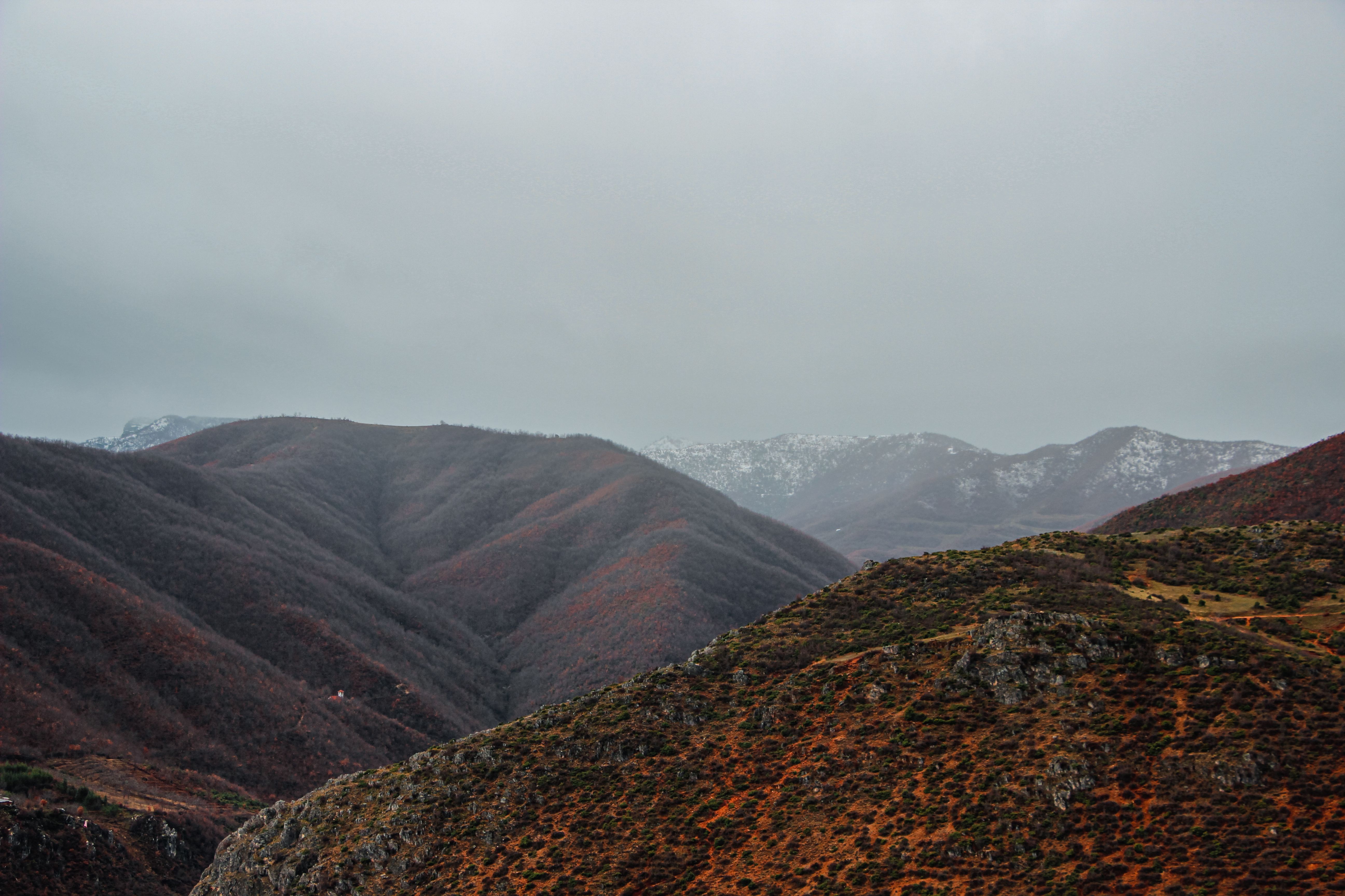 Breathtaking landscape of Swiss Alps with hills and valleys under a cloudy sky.