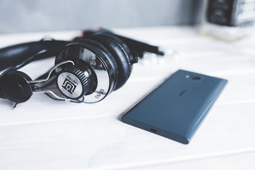 Black headphones and a smartphone on a wooden surface, emphasizing modern technology.