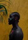 Black guy with painted face and body on yellow surface