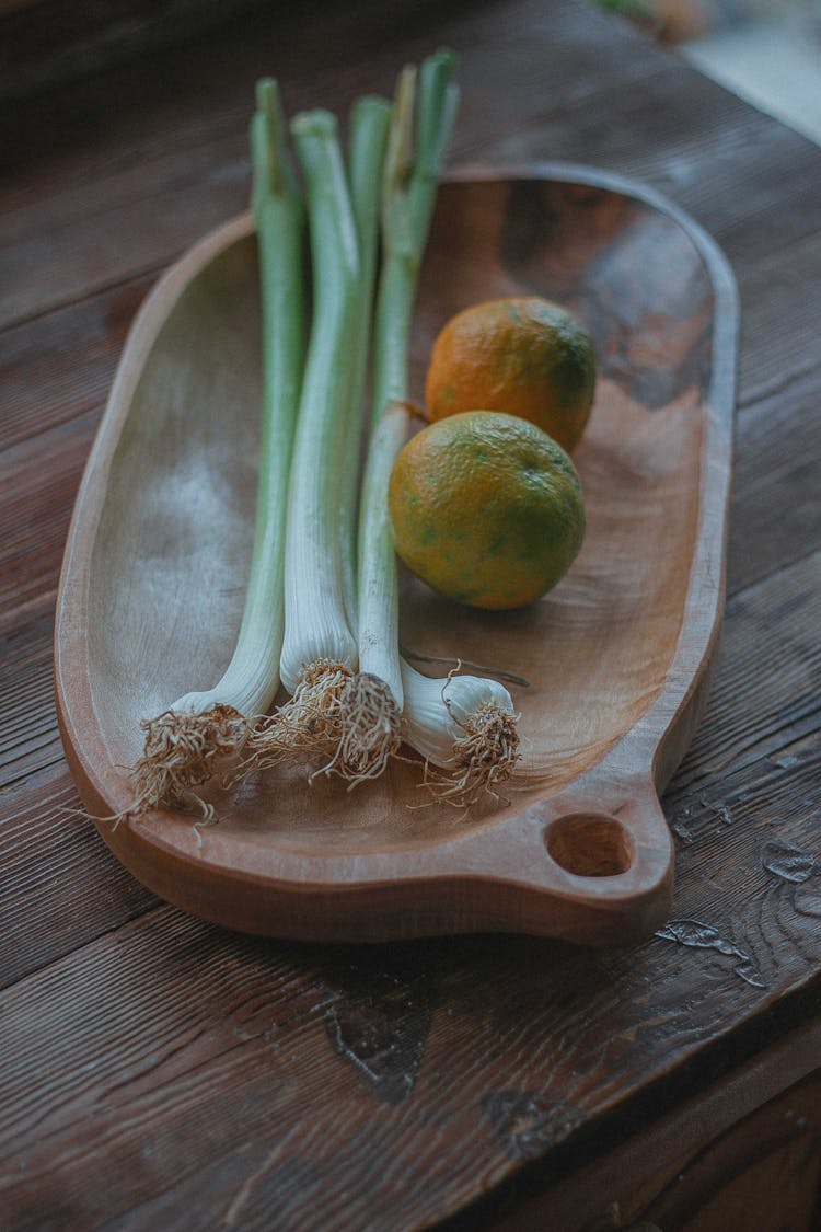 Onion Leeks And Orange Fruits On Brown Wooden Platter