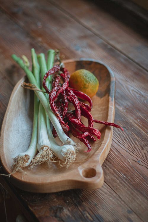 Onion Leaks and Red Peppers on Wooden Oval Bowl