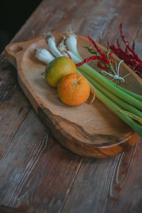 Photo of Oranges and Spring Onions on a Chopping Board