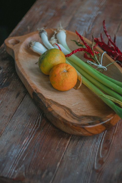 Free A rustic display of fresh oranges, chili peppers, and green onions on a wooden chopping board. Stock Photo