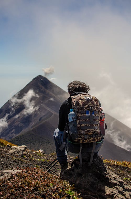 A Man Sitting on the Rock Formation on the Mountain