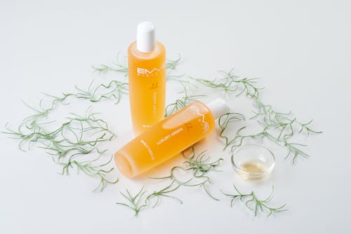 Orange Cosmetics and Grass Blades on White Background