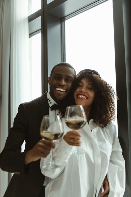 Man Standing Behind a Woman While Holding Wine Glasses