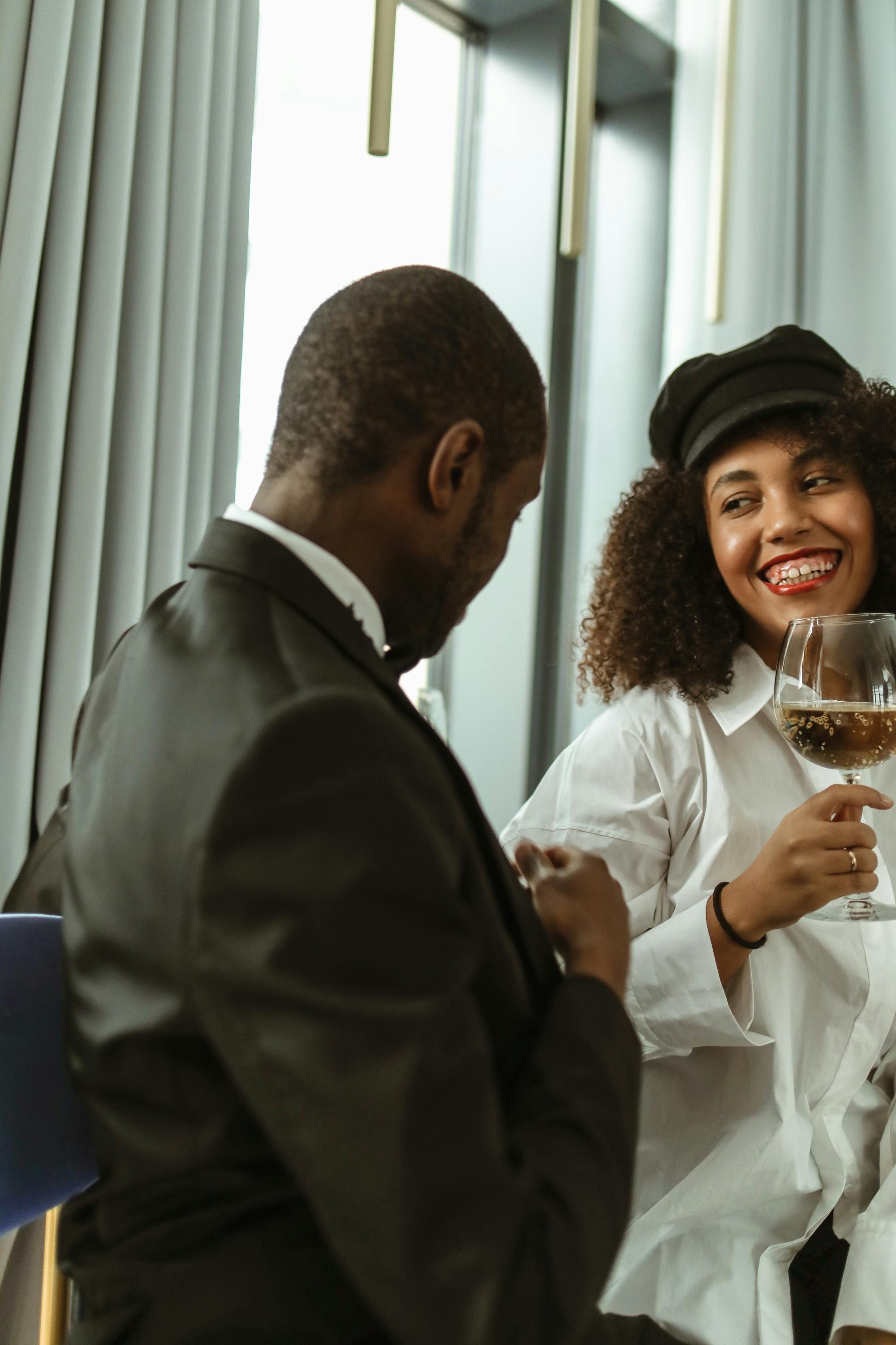 A cheerful couple shares a joyful moment with wine indoors, perfect for lifestyle and relationship themes.