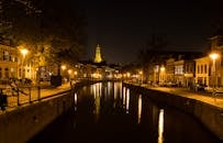 格罗宁根运河的夜景中，教堂塔楼和街灯倒映在水面上