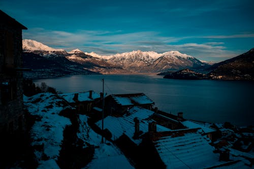 Small village near lake and snowy mountains in evening