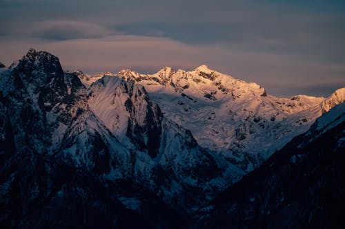 Scenic snowy highlands under cloudy sundown sky