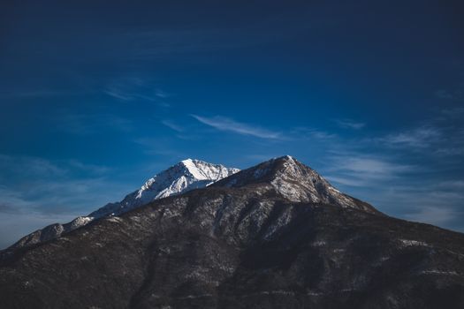 Spectacular alpine landscape with rocky mountains with snowy peaks against bright blue sky on winter day