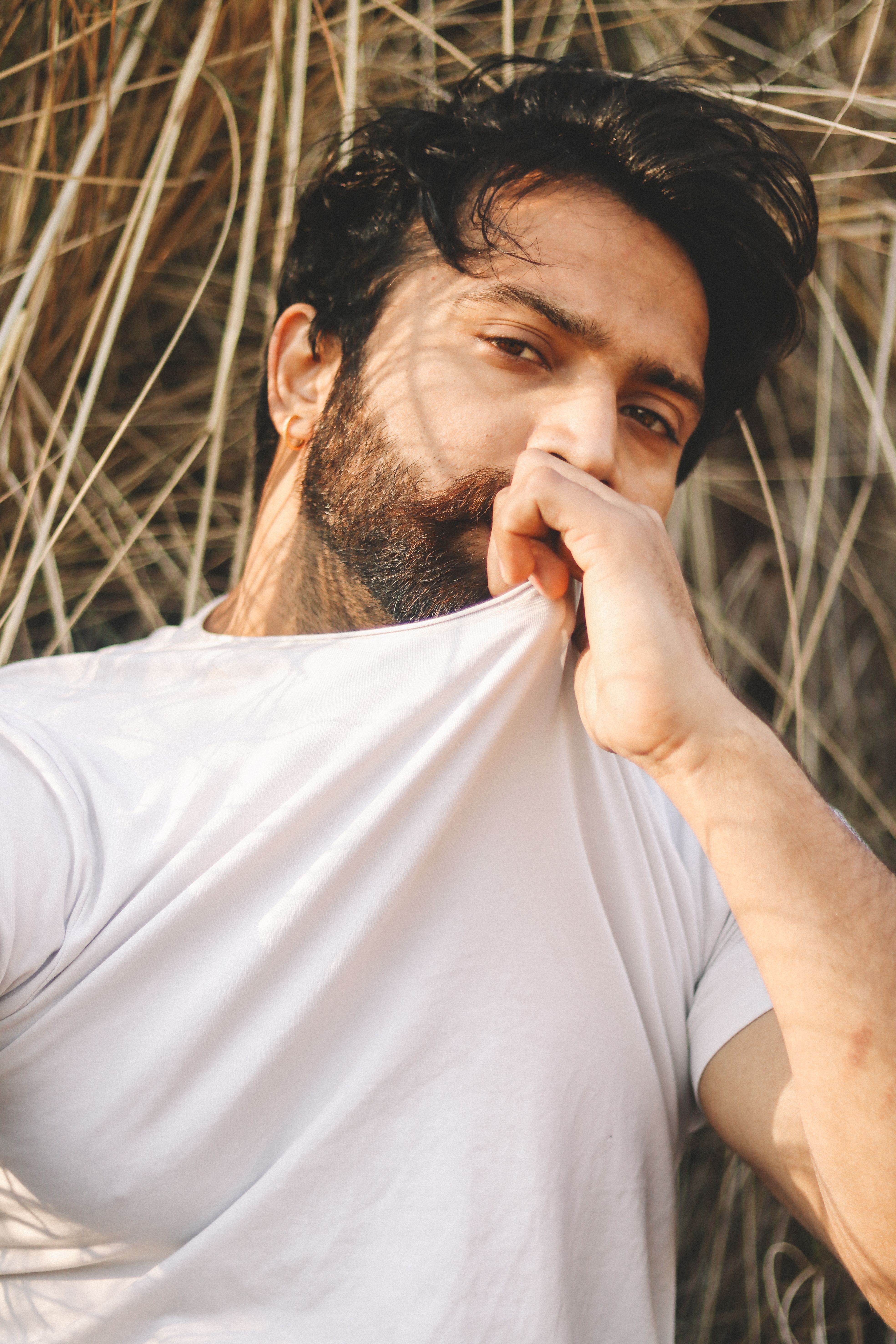 Close-up portrait of a bearded man in a white shirt outdoors, showcasing a thoughtful pose.