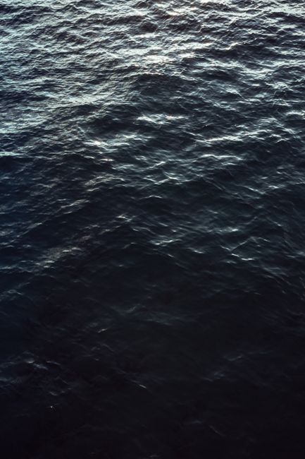 A captivating close-up of dark ocean waves reflecting light, ideal for mobile wallpaper.